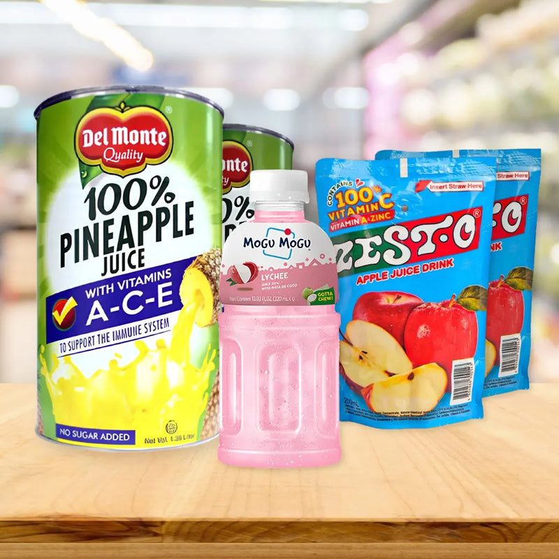 Juice drink display featuring a Del Monte Pineapple Juice can on the left, a Mogu Mogu Lychee bottle in the center, and two Zesto Apple pouches on wood.