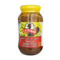 A jar of sauteed shrimp paste sits against a black background, showcasing its creamy texture and vibrant yellow color.