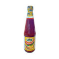 A bottle of hot sauce with a vibrant label, set against a solid black background.